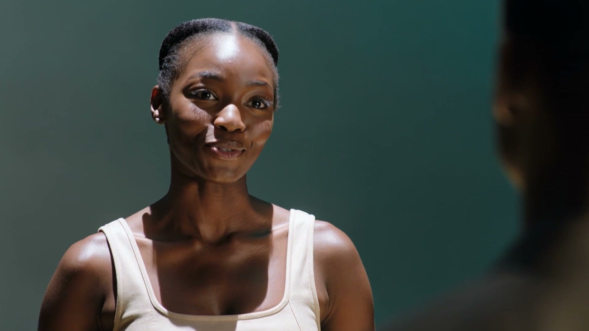 A smiling young woman in a teal studio, from the Bluebell brand film